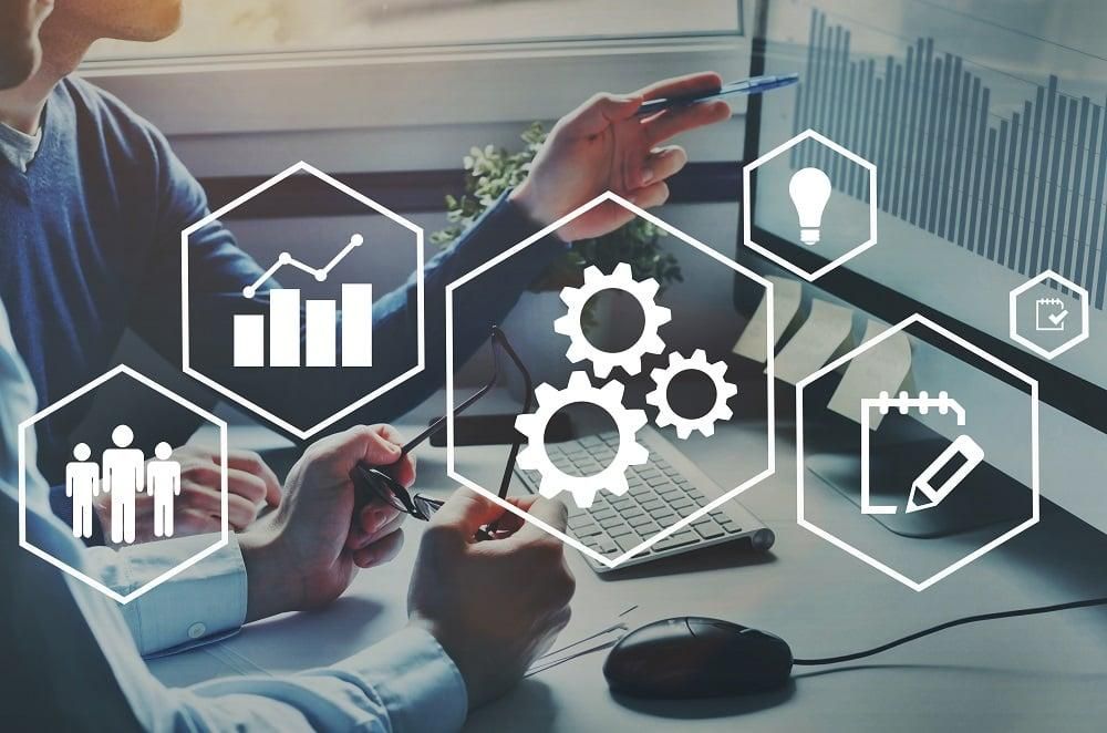 An image depicting business strategy or collaboration, with a computer screen showing a graph and hands interacting, enhanced by digital icons for planning, operations, and innovation.