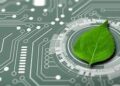 A fresh green leaf placed on an electronic circuit board with glowing lines, representing the integration of nature and technology or sustainable tech.