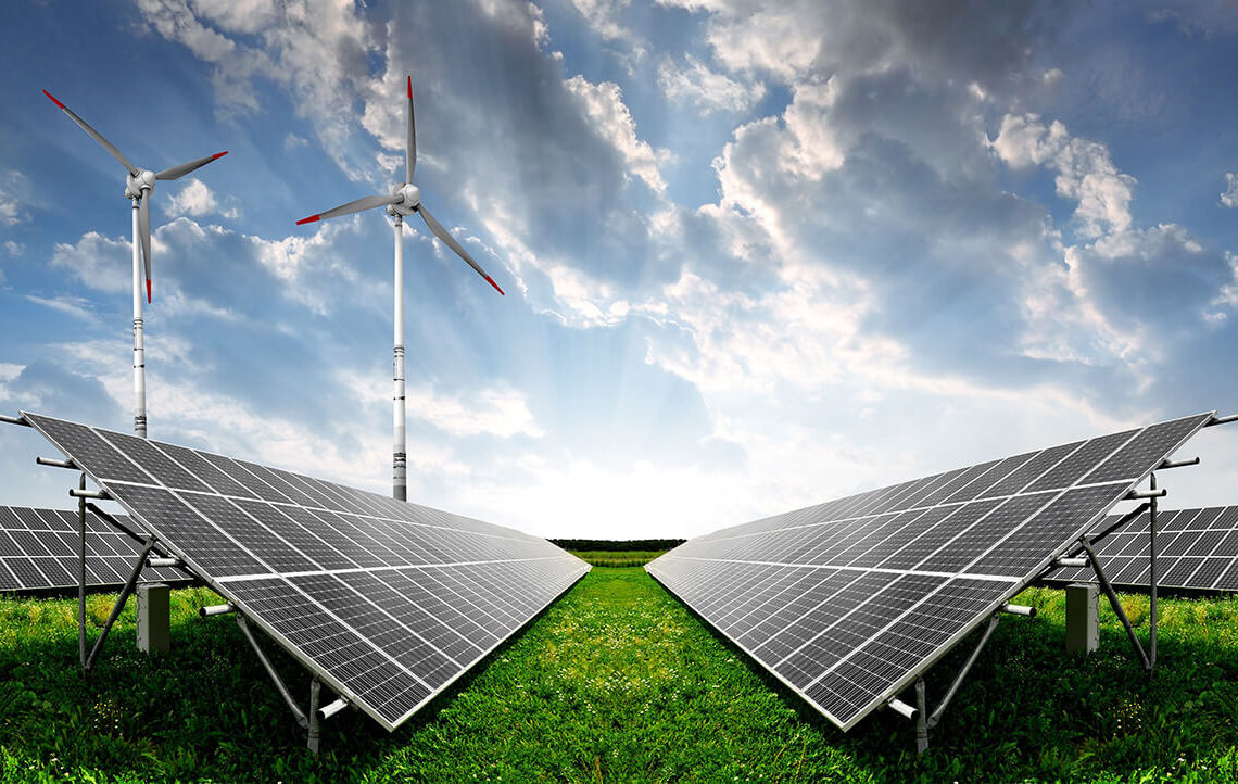 Solar panels and wind turbines in a green field under a cloudy sky, representing renewable energy.