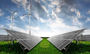 Solar panels and wind turbines in a green field under a cloudy sky, representing renewable energy.