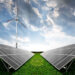Solar panels and wind turbines in a green field under a cloudy sky, representing renewable energy.
