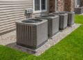 Multiple large HVAC outdoor condenser units installed along the side of a residential or commercial building.