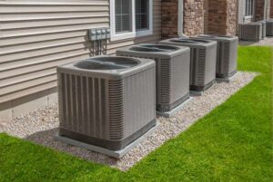 Multiple large HVAC outdoor condenser units installed along the side of a residential or commercial building.