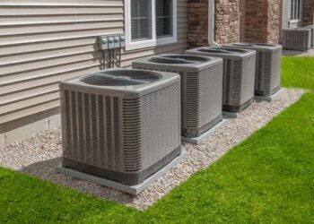 Multiple large HVAC outdoor condenser units installed along the side of a residential or commercial building.